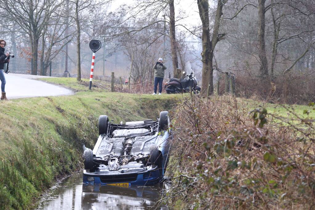 Auto vliegt uit bocht en komt ondersteboven in sloot