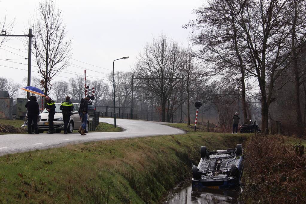 Auto vliegt uit bocht en komt ondersteboven in sloot