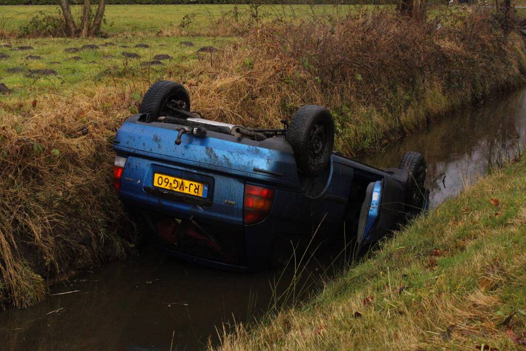 Auto vliegt uit bocht en komt ondersteboven in sloot