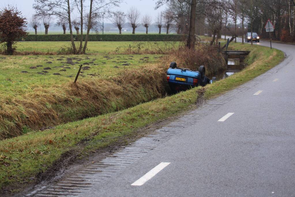 Auto vliegt uit bocht en komt ondersteboven in sloot