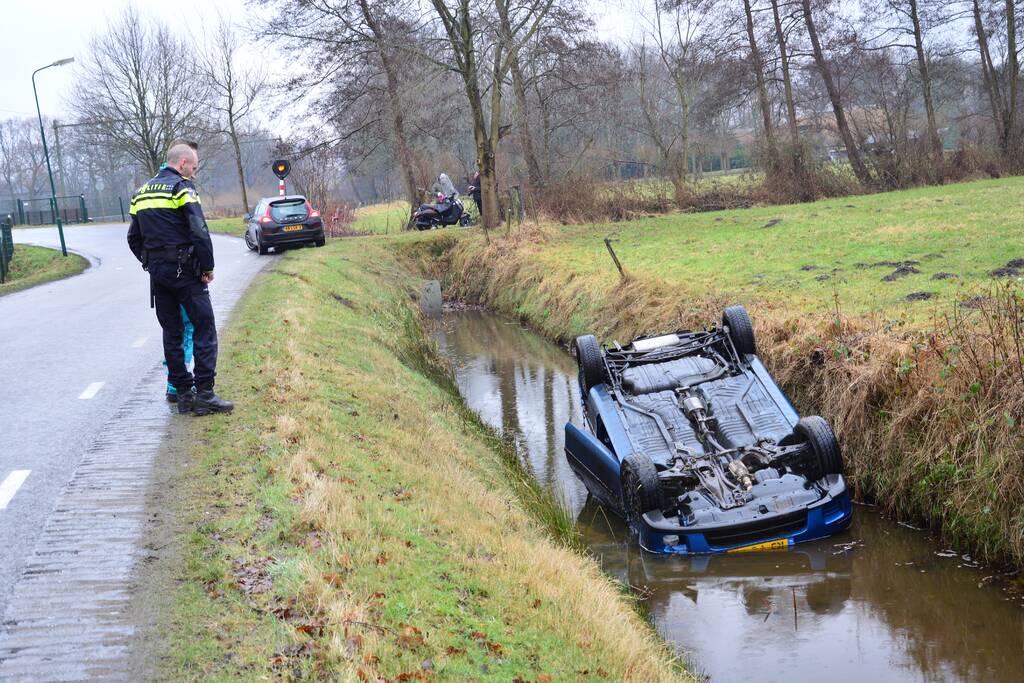 Auto vliegt uit bocht en komt ondersteboven in sloot