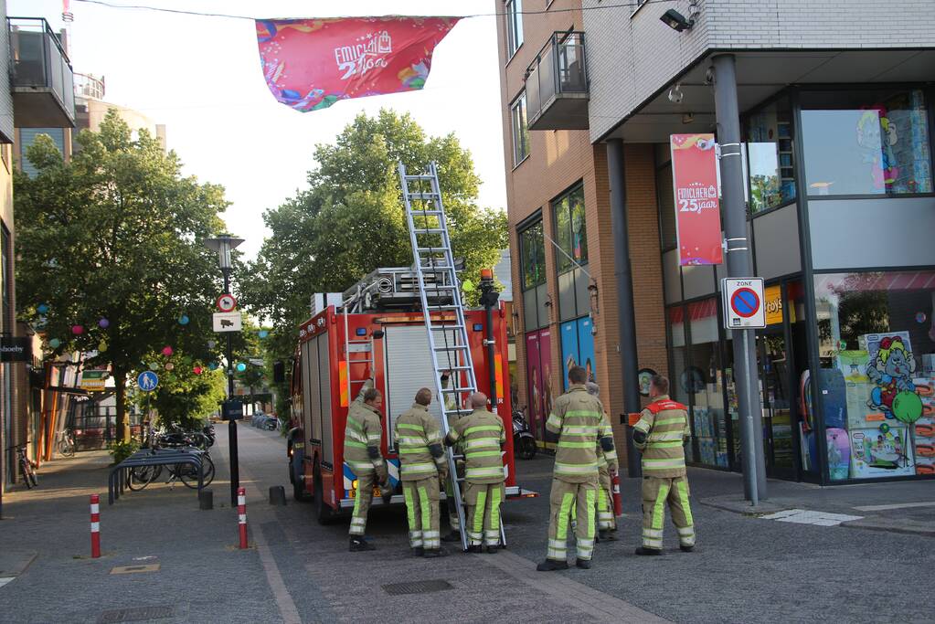 Brandweer zet loshangend reclamedoek vast