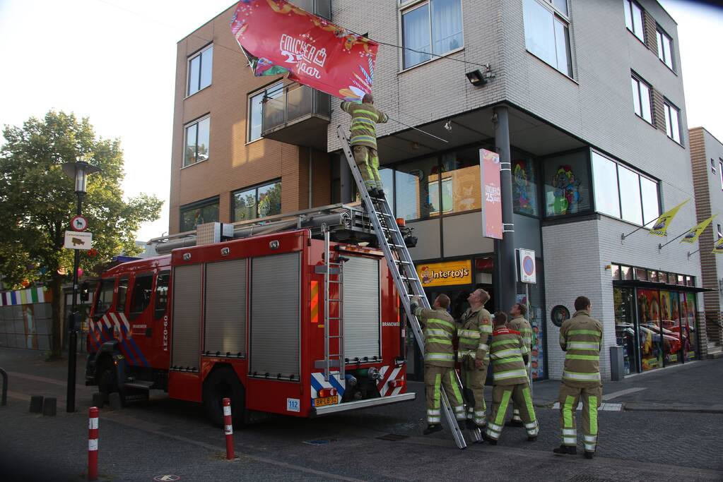 Brandweer zet loshangend reclamedoek vast