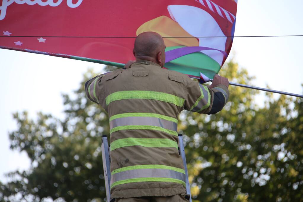 Brandweer zet loshangend reclamedoek vast