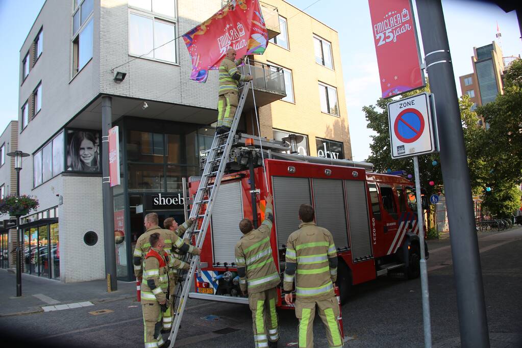 Brandweer zet loshangend reclamedoek vast