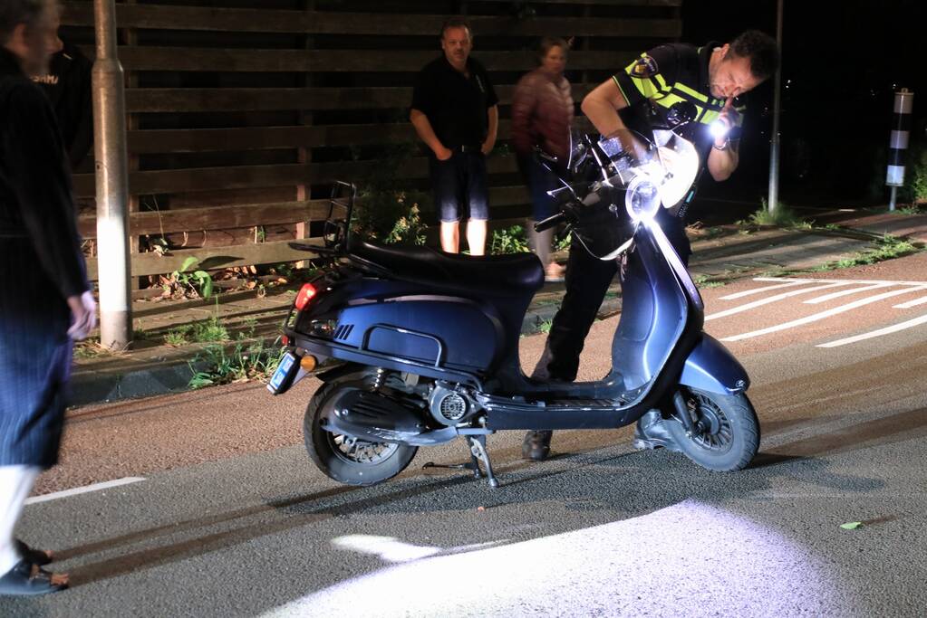 Snorscooter klapt op paal bij oversteekplaats, jonge dame buiten westen