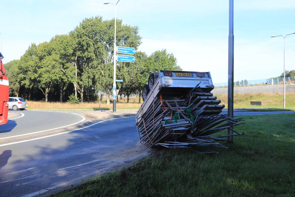 Aanhangwagen met steigerdelen kantelt