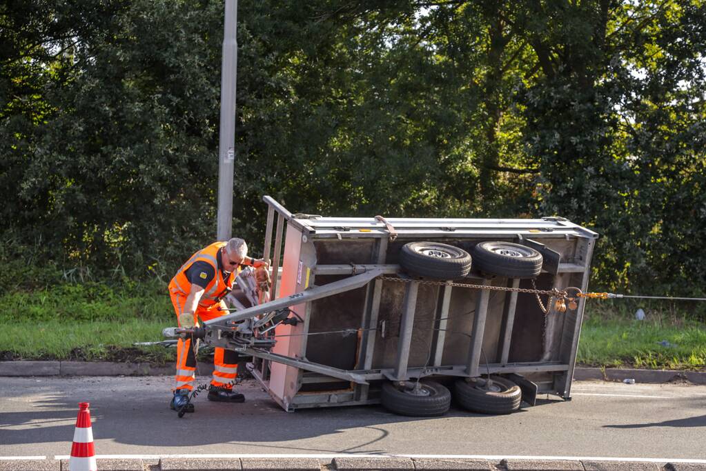 Aanhangwagen met steigerdelen kantelt