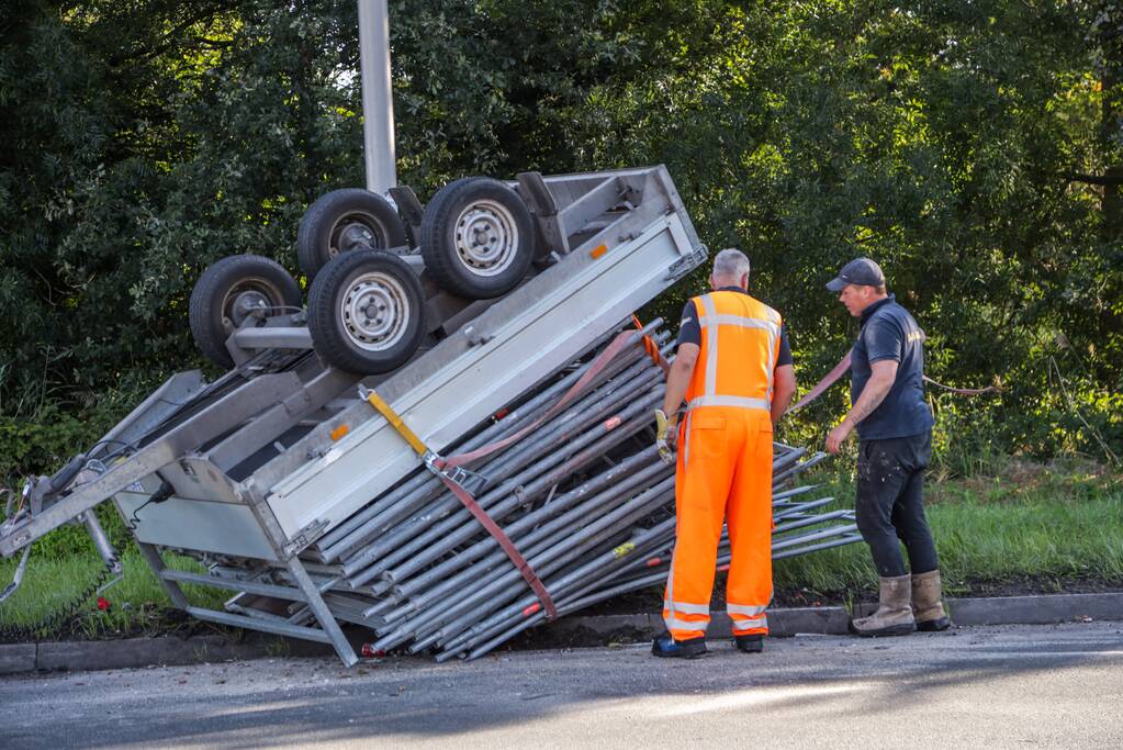 Aanhangwagen met steigerdelen kantelt