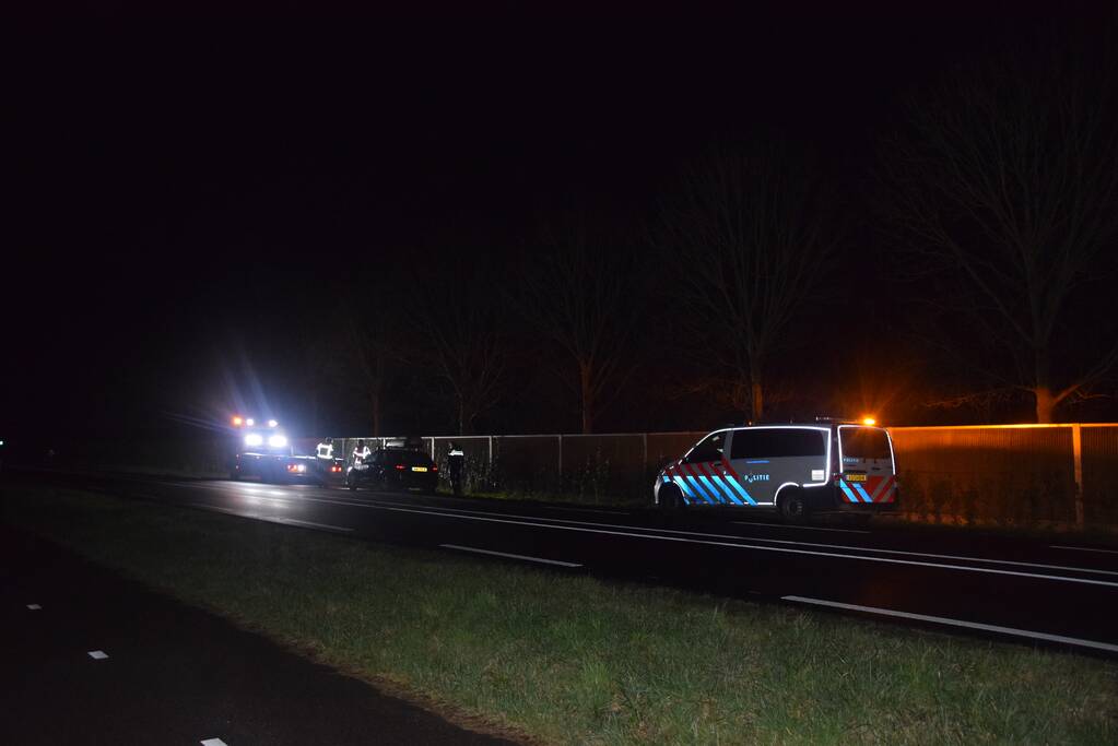 Politieauto en personenauto beschadigd door stenen op rijbaan