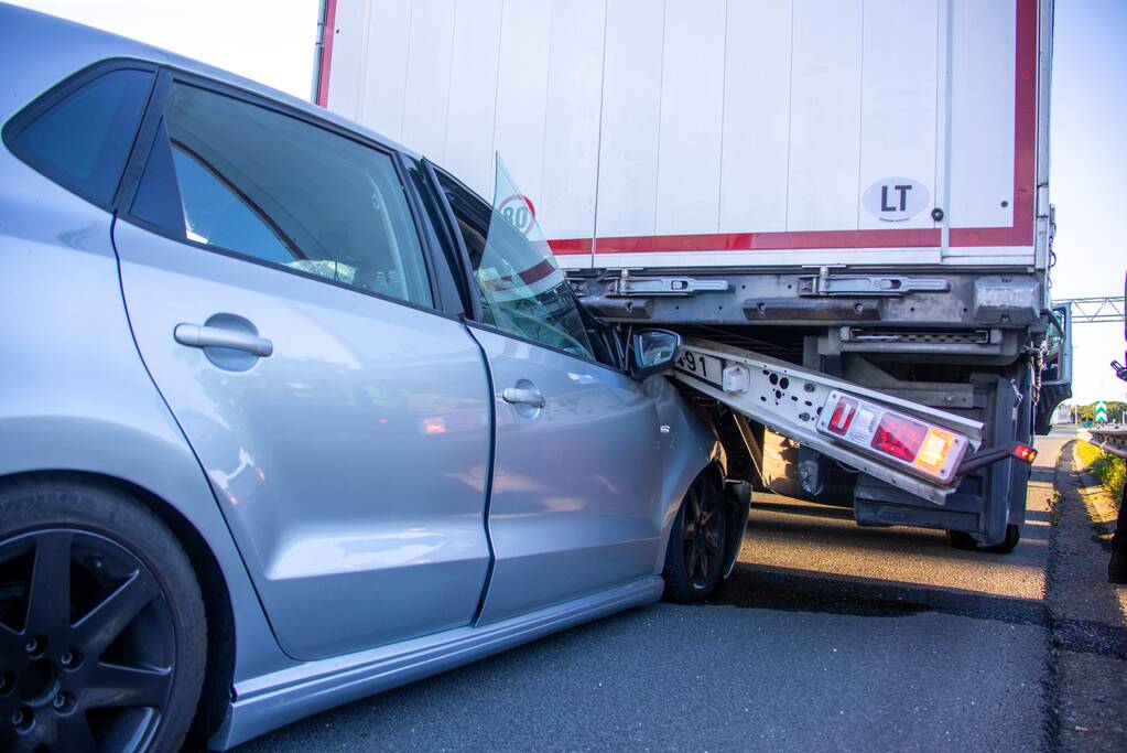 Auto schiet onder oplegger vrachtwagen