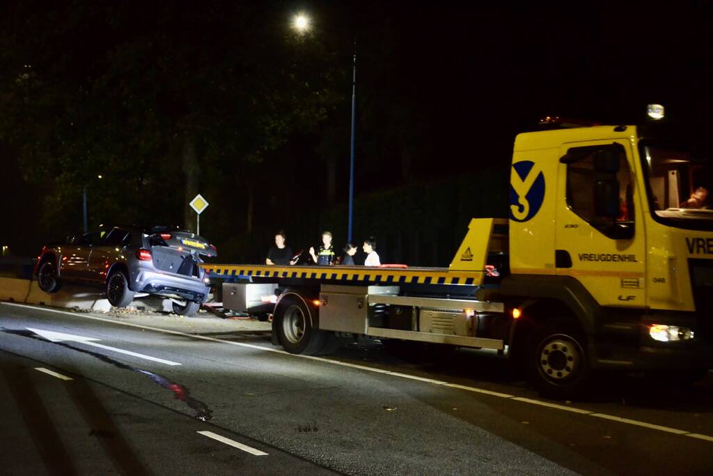 Auto belandt bovenop betonnen afscheiding