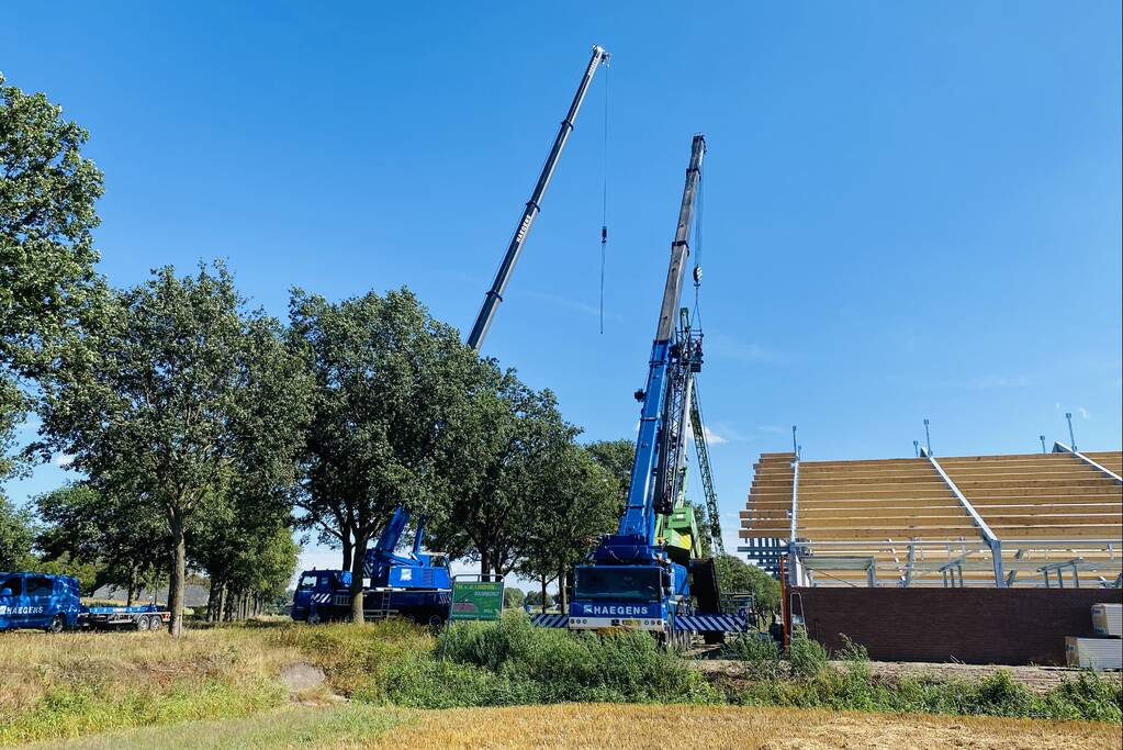 Bouwkraan achter stal omgevallen