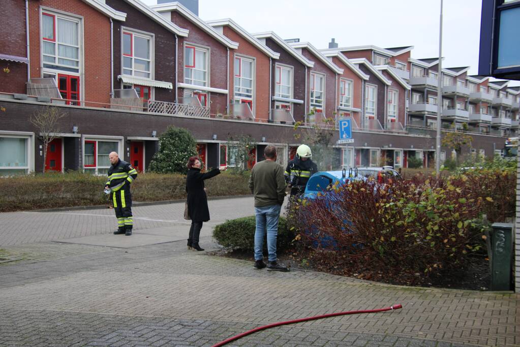 Omstanders blussen brand in papiercontainer