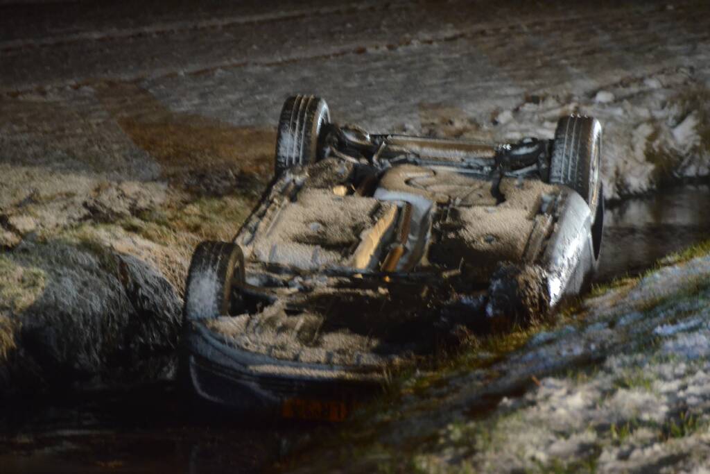 Auto glijdt van de weg en belandt op de kop in sloot