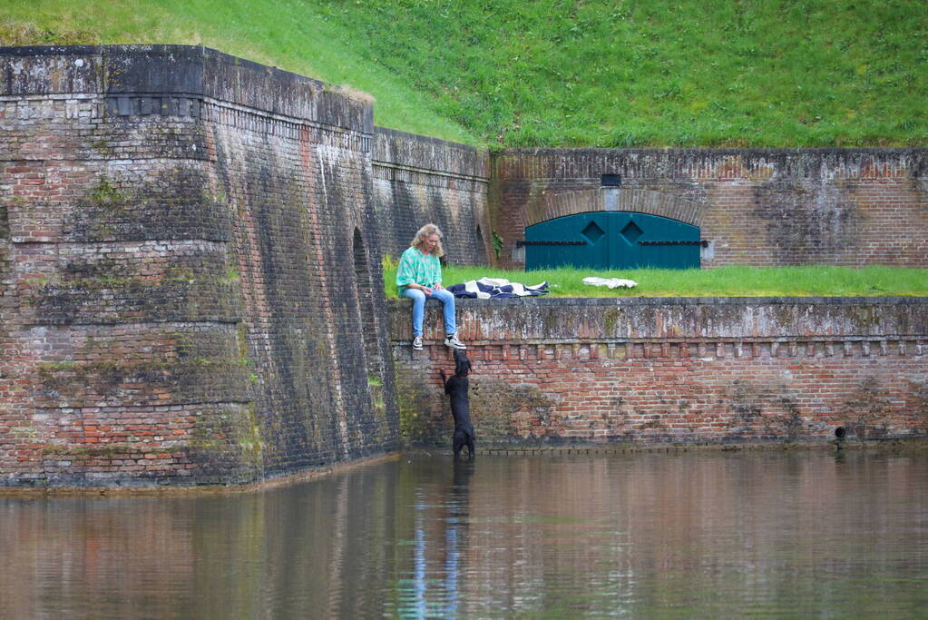 Hond valt van meters hoge vestingwal in water