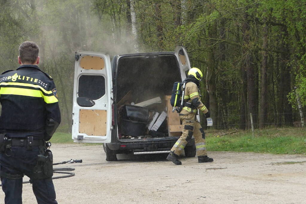 Bestelbus met afval in brand gestoken op parkeerplaats bij bos, twee aanhoudingen