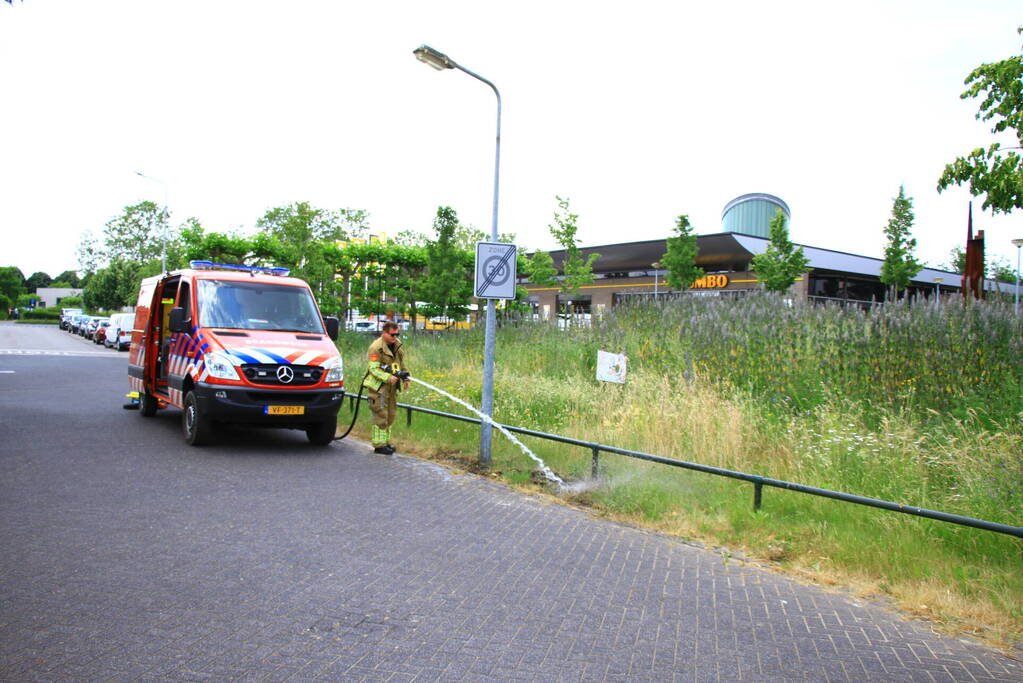 Berm in brand bij winkelcentrum