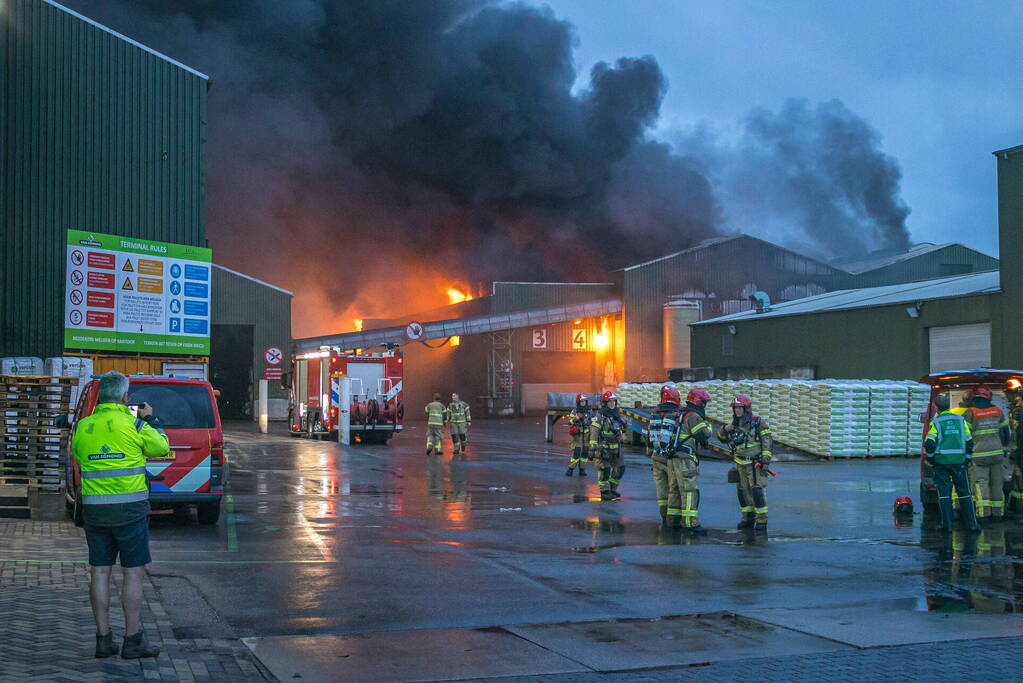 Zwarte rookpluimen boven havengebied door grote brand