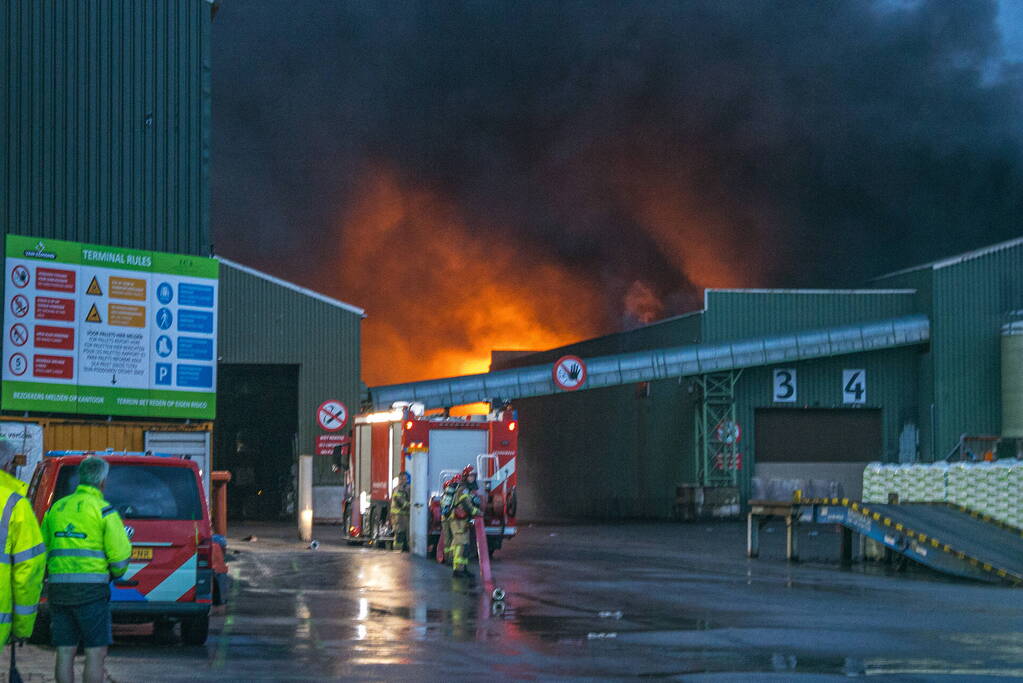 Zwarte rookpluimen boven havengebied door grote brand