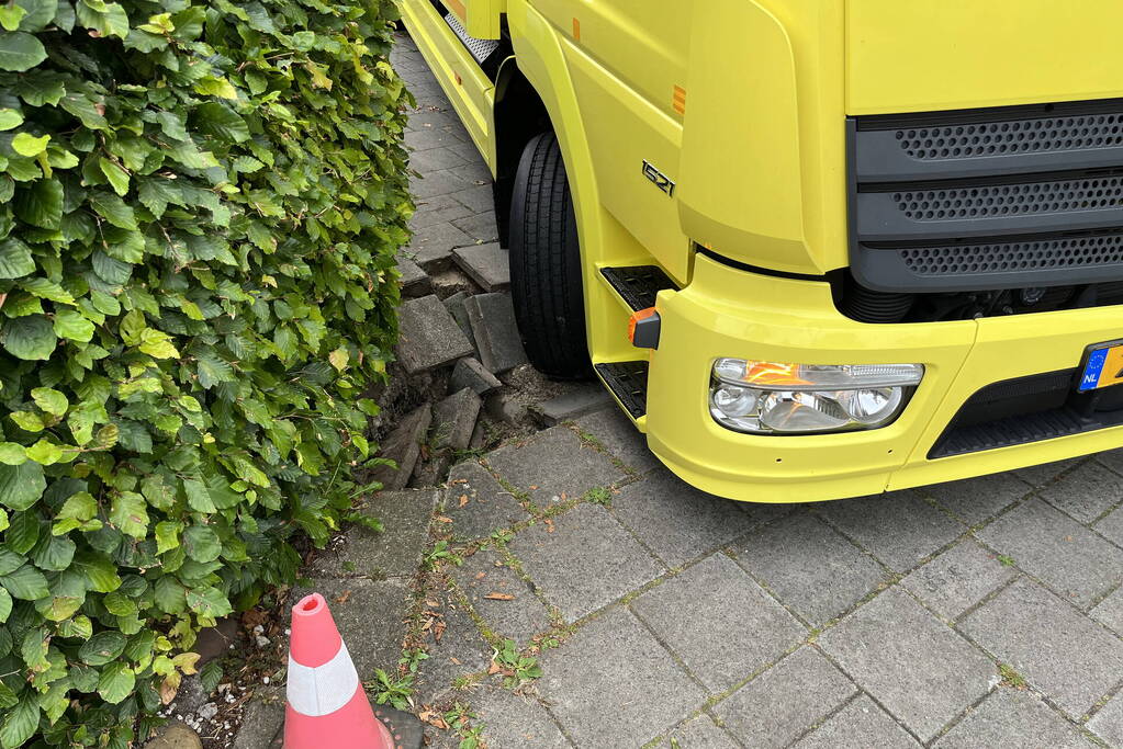 Vrachtwagen zakt weg in stoep