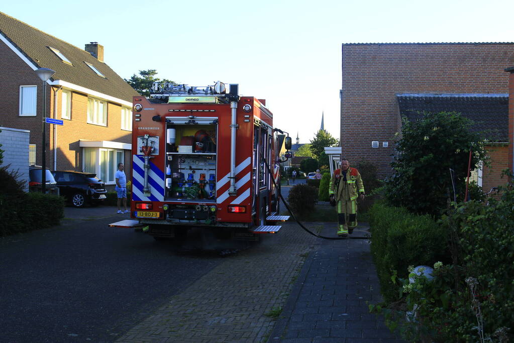 Brandweer blust brandende prullenbak in schuur