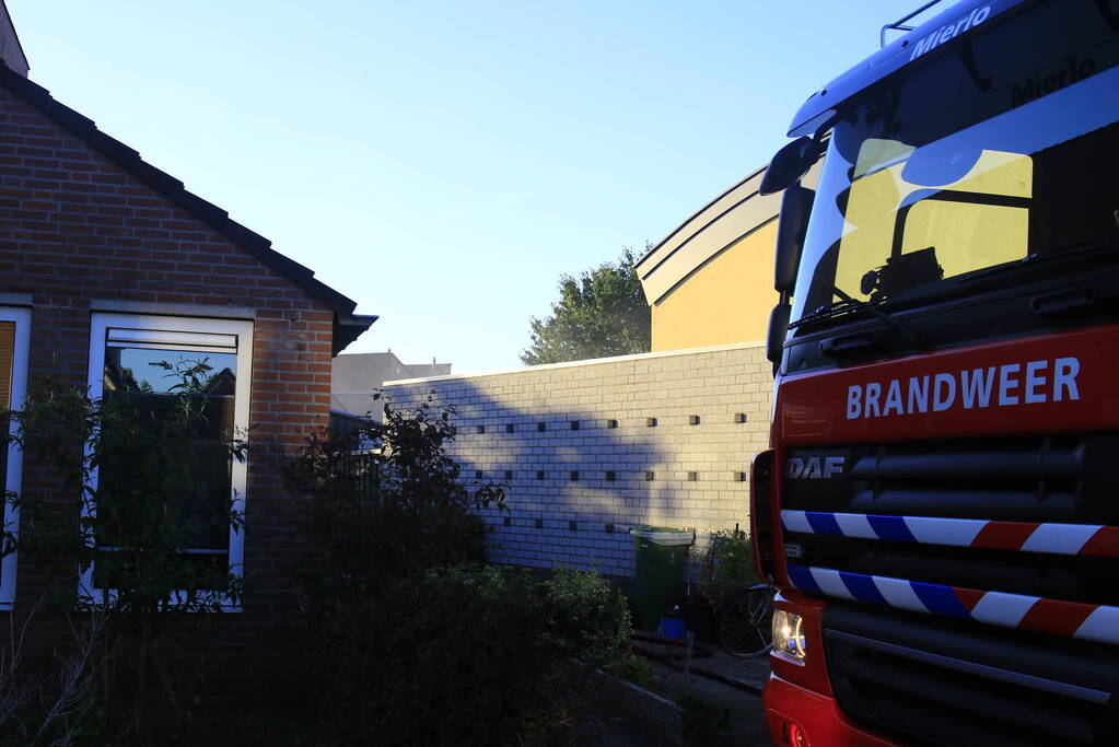 Brandweer blust brandende prullenbak in schuur