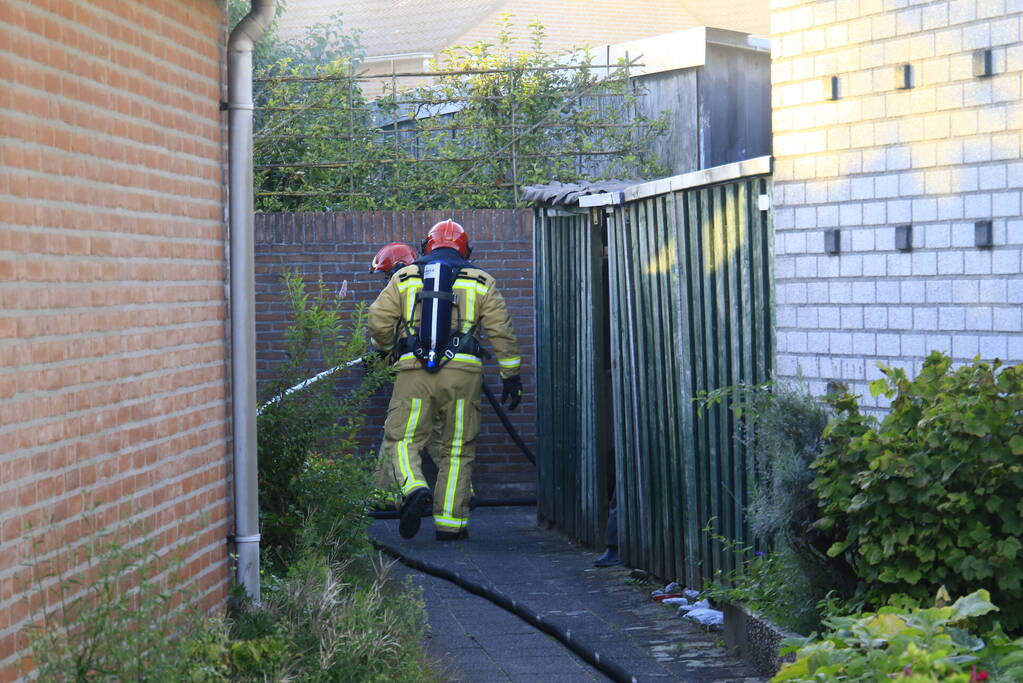 Brandweer blust brandende prullenbak in schuur