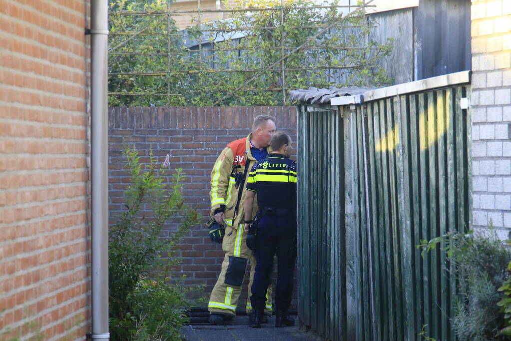 Brandweer blust brandende prullenbak in schuur