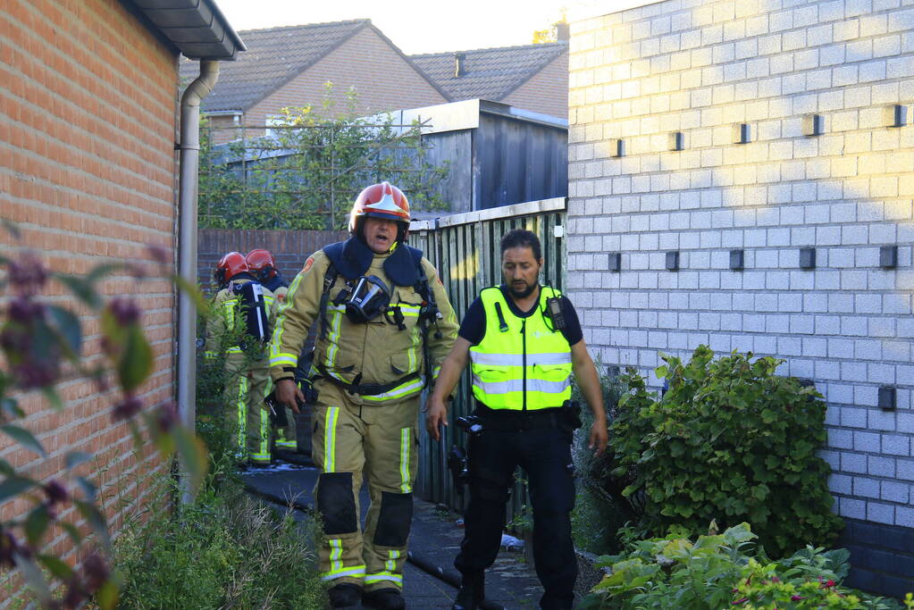 Brandweer blust brandende prullenbak in schuur