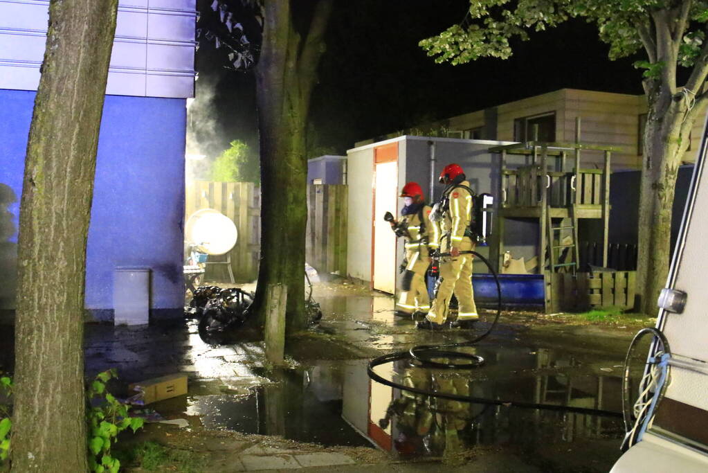 Scooter in brand tegen woning