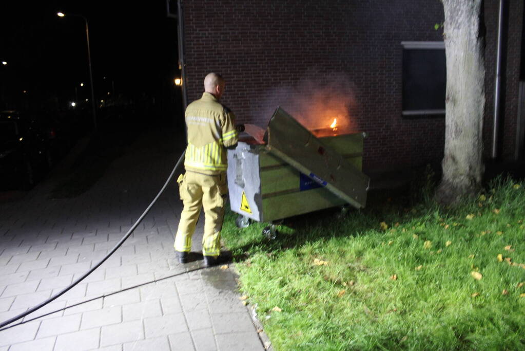 Vlammen slaan uit afvalcontainer