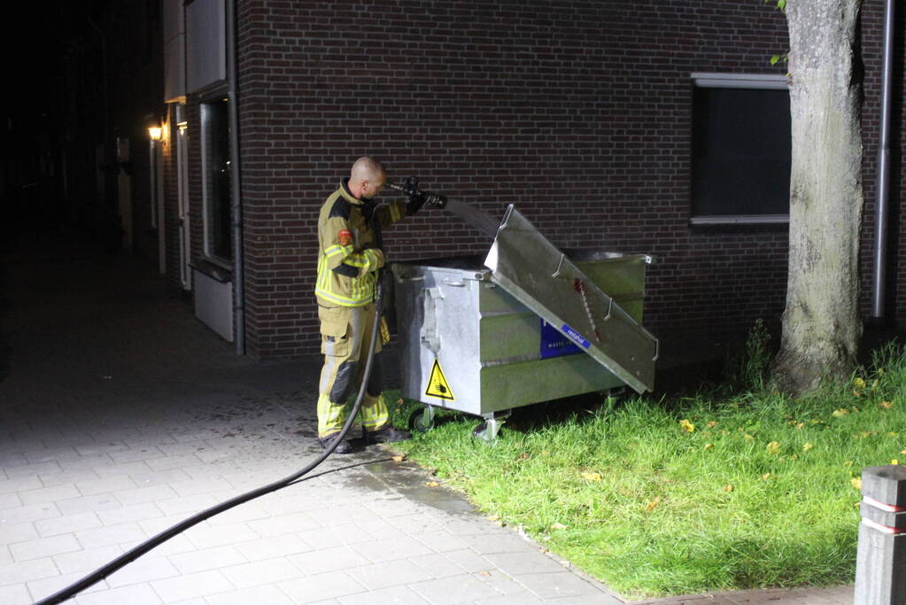 Vlammen slaan uit afvalcontainer