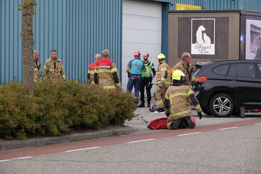 Scooterrijder bekneld onder auto