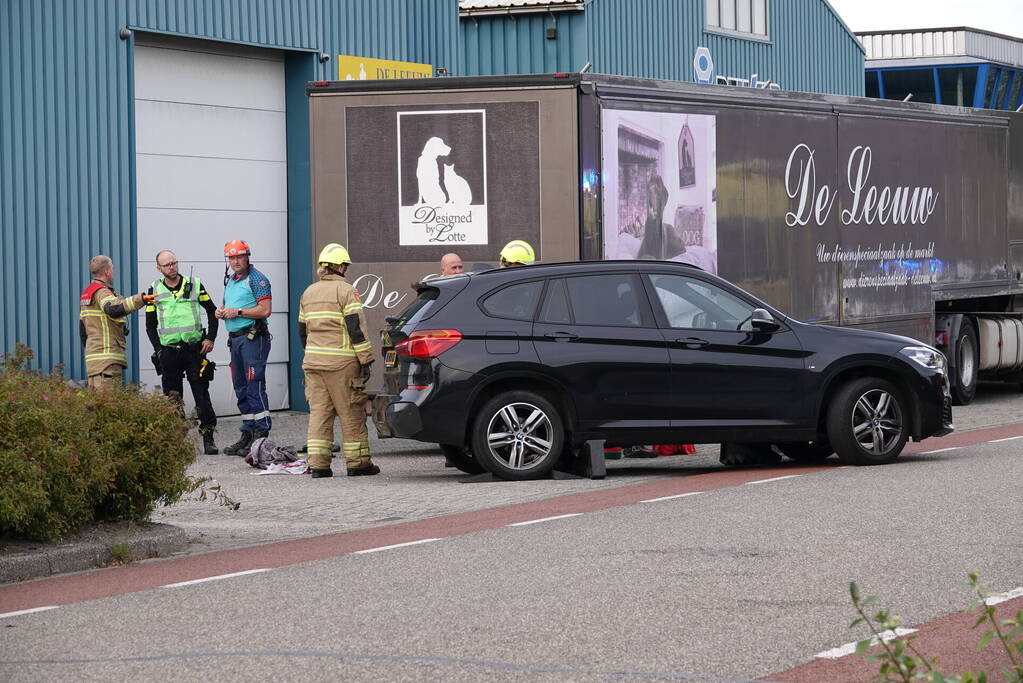 Scooterrijder bekneld onder auto