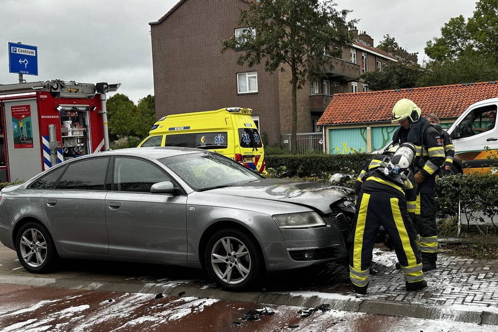 Brandweer blust brand in motorcompartiment van auto