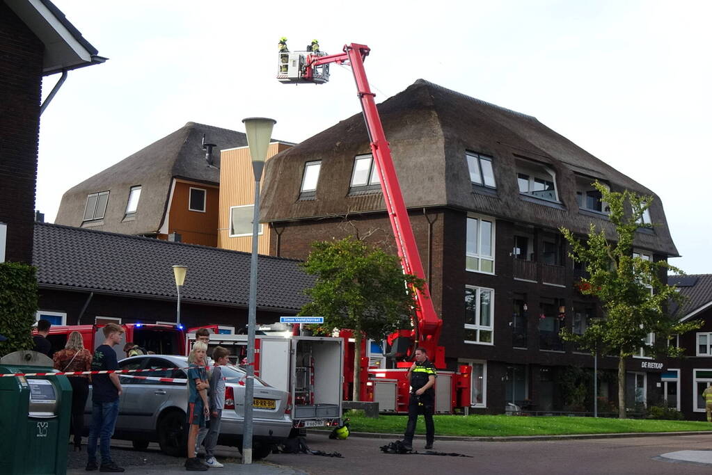 Brand op dak van appartementencomplex met rietendak