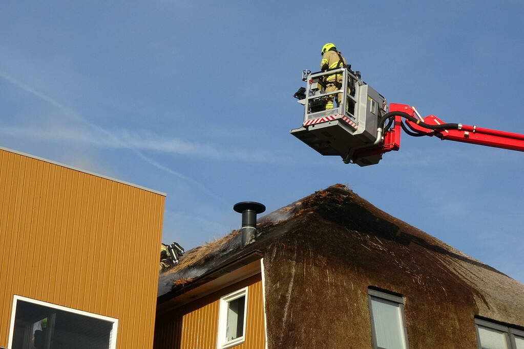 Brand op dak van appartementencomplex met rietendak