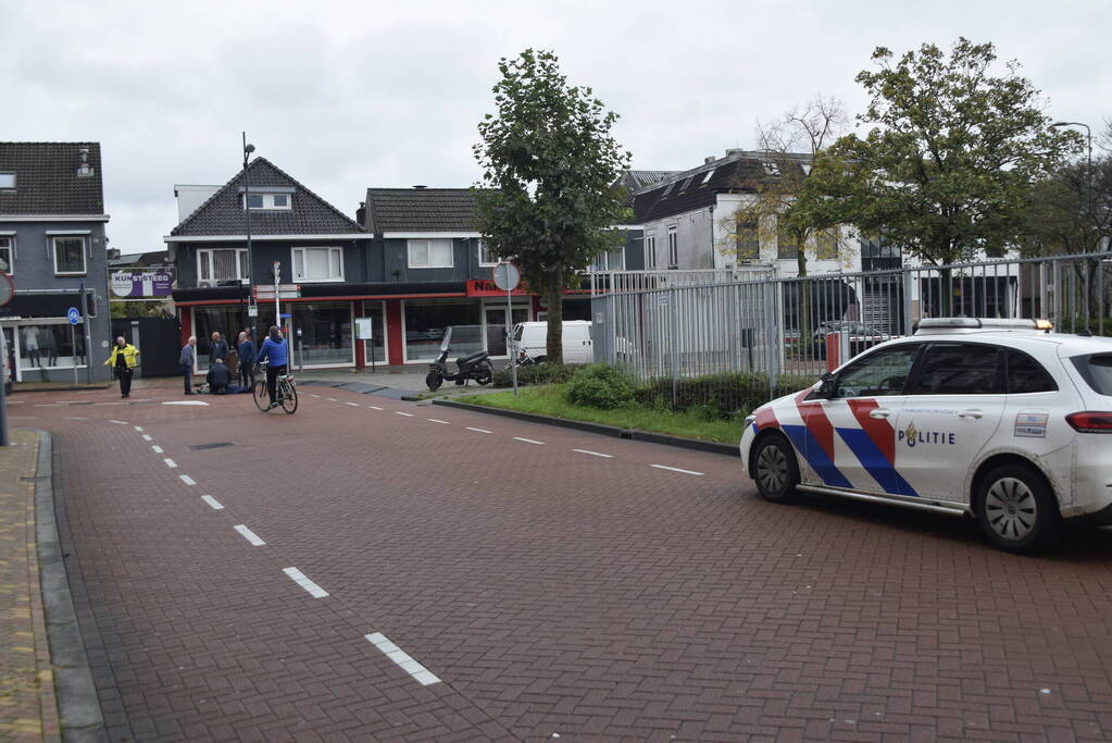 Persoon op scooter onderuit op kruising