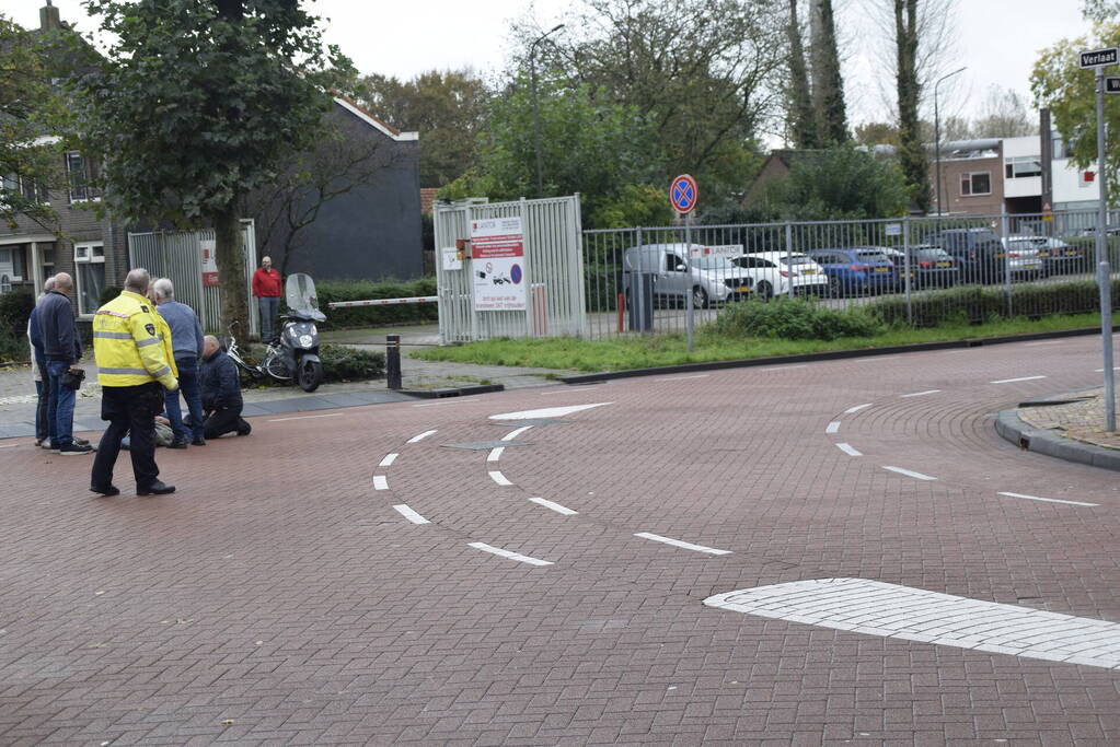 Persoon op scooter onderuit op kruising