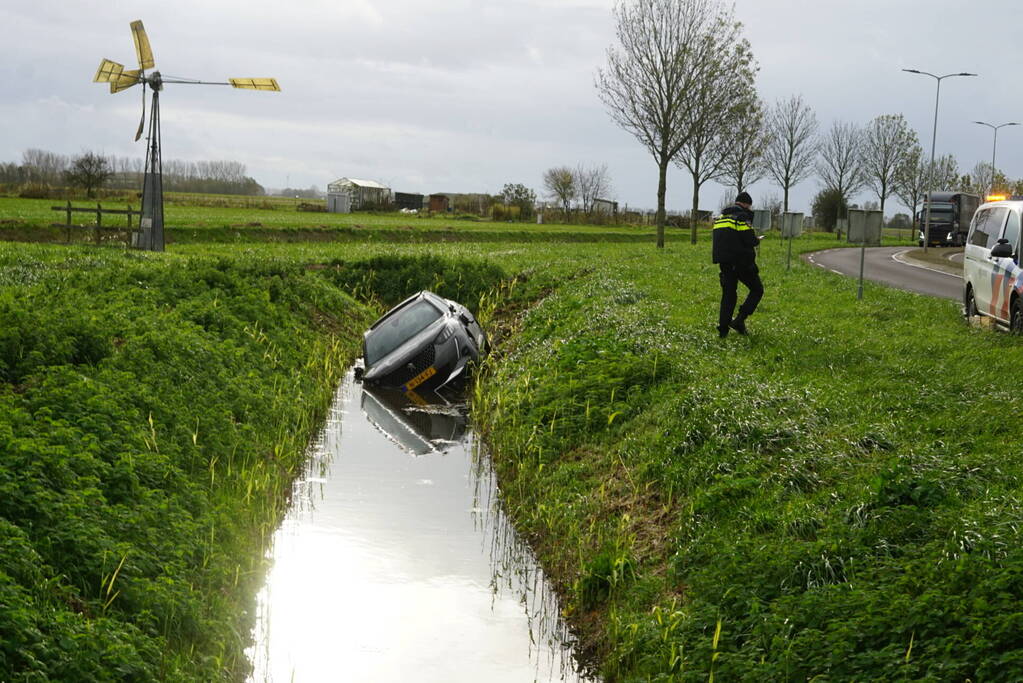 Omstanders halen inzittenden uit te water geraakt voertuig