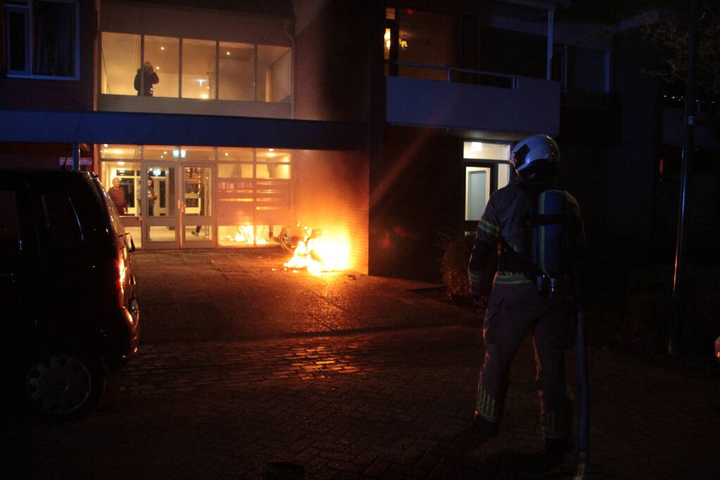 Brandweer blust brandende scooter tegen appartementencomplex