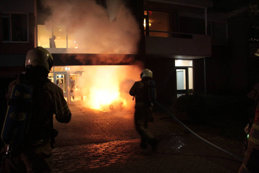 Brandweer blust brandende scooter tegen appartementencomplex