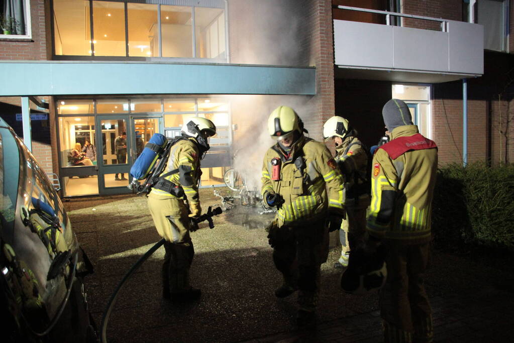 Brandweer blust brandende scooter tegen appartementencomplex