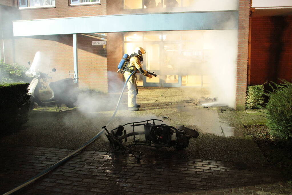 Brandweer blust brandende scooter tegen appartementencomplex