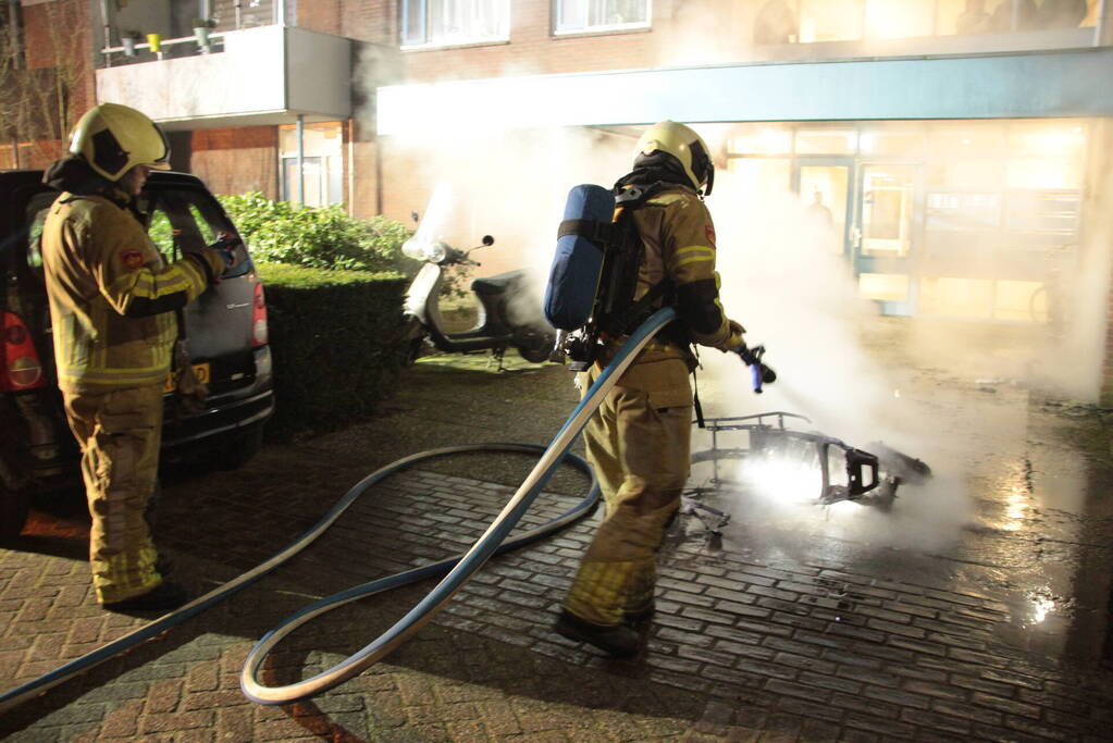 Brandweer blust brandende scooter tegen appartementencomplex