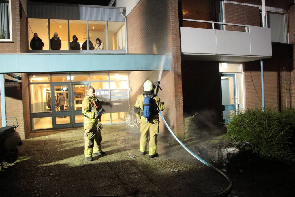 Brandweer blust brandende scooter tegen appartementencomplex