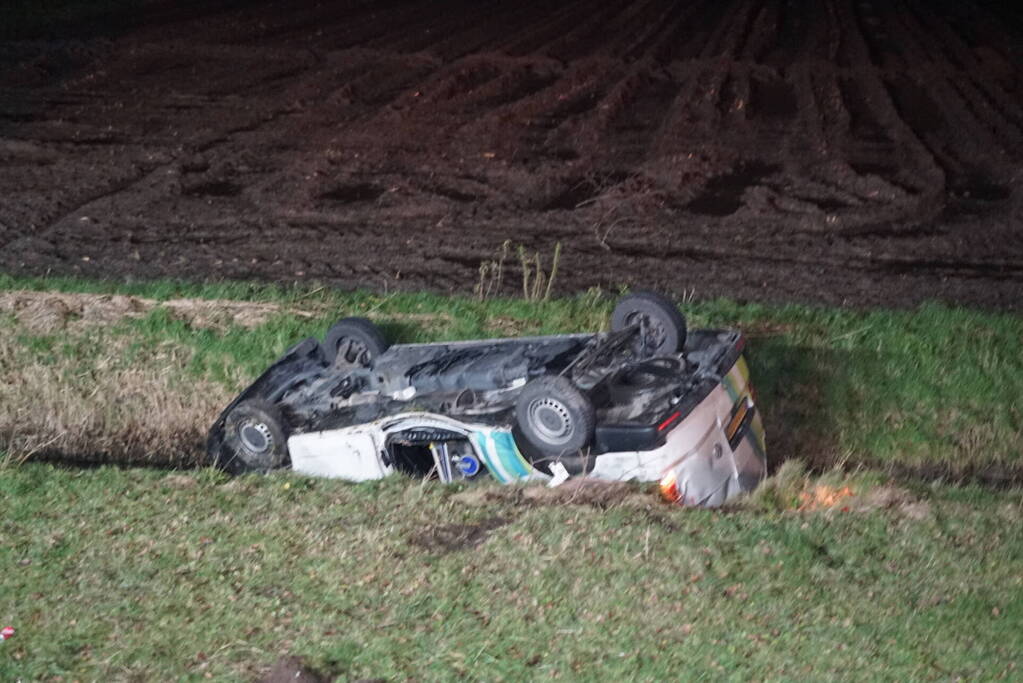 Auto raakt van weg, schampt boom en belandt ondersteboven in de sloot