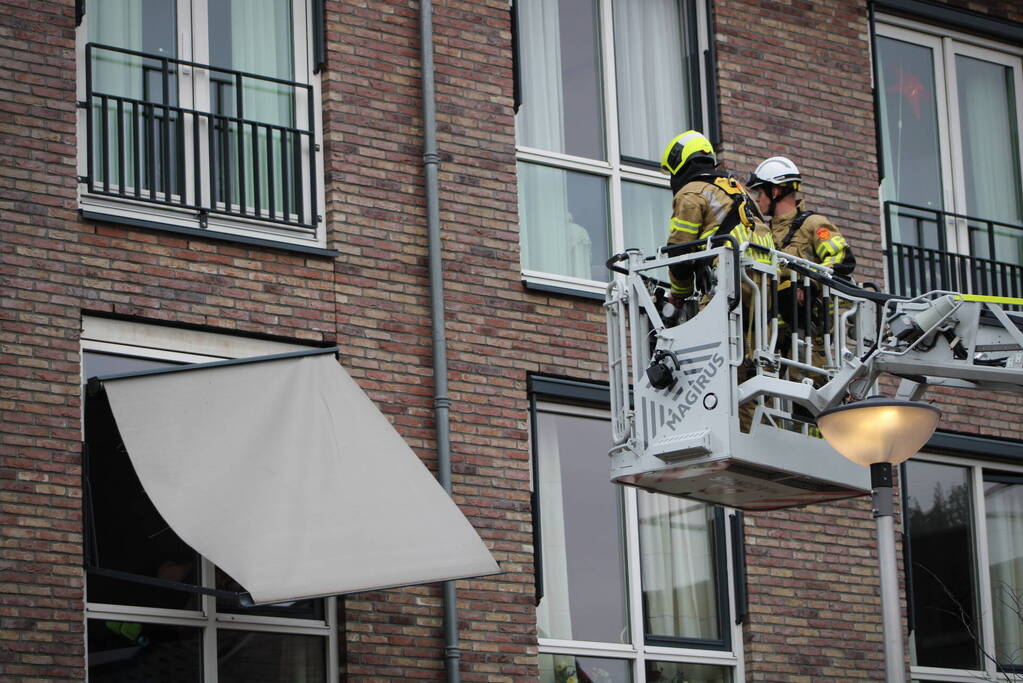 Brandweer zet loshangende zonnescherm vast