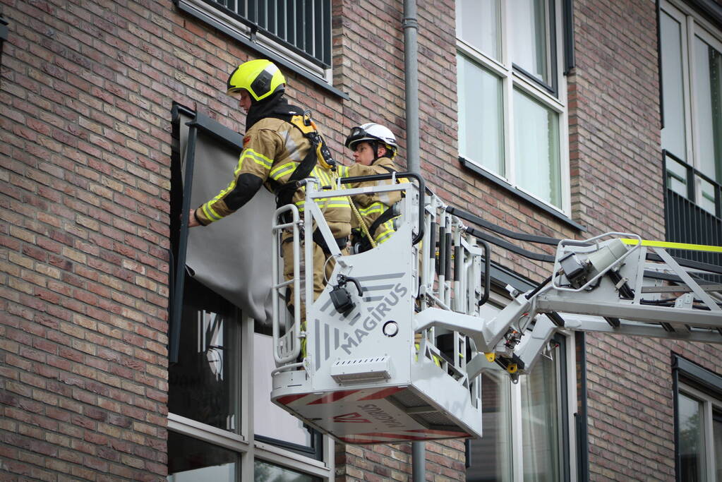 Brandweer zet loshangende zonnescherm vast